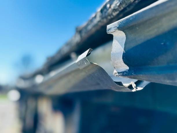 Close-up of a hanger bracket clipped over the front lip of an aluminum gutter.